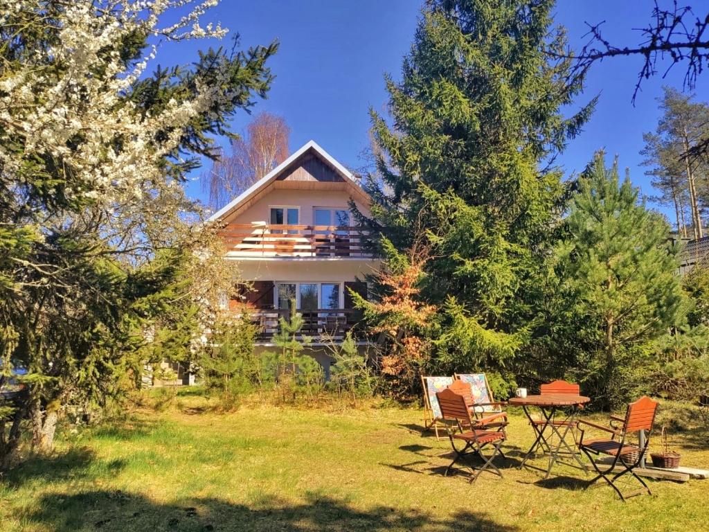 a house with a table and chairs in the yard at Dom Widny Jaś zaprasza nad jezioro na Kaszuby in Sulęczyno