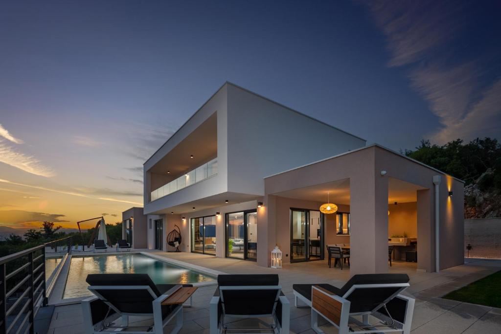 a large house with a swimming pool and chairs at Villa Dujma Pool & Spa in Kostrena