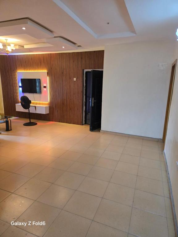 a large room with a white wall and a chair at De Royal Lodge in Abaranjeh