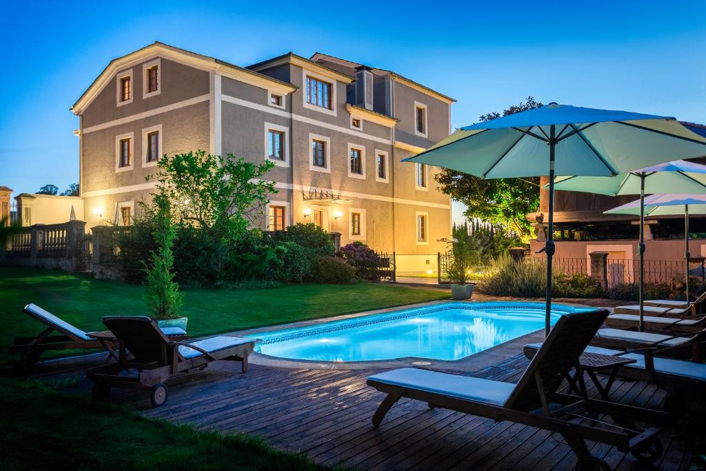 a pool with chairs and an umbrella next to a building at Casa de Castro in Cartavio