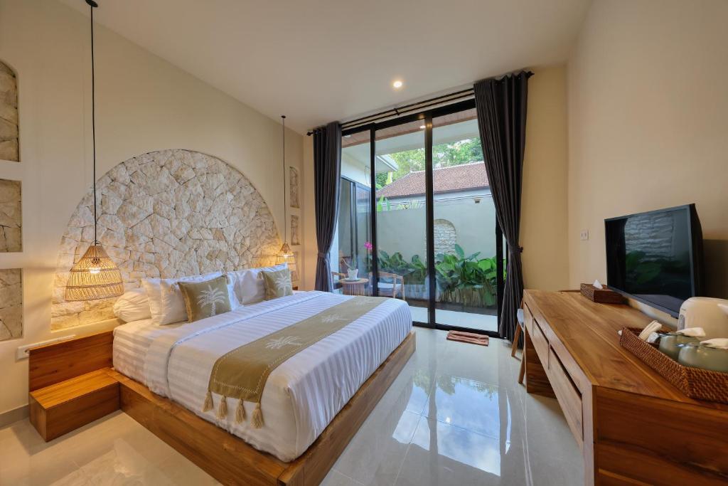 a bedroom with a large bed and a television at Rest U Guest House in Nusa Penida