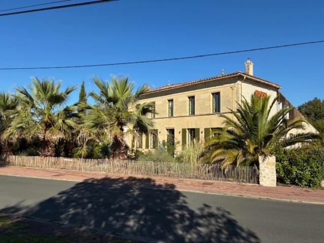 a large building with palm trees in front of it at Villa l'Estuaire Chambres d'Hôtes in Braud-et-Saint-Louis