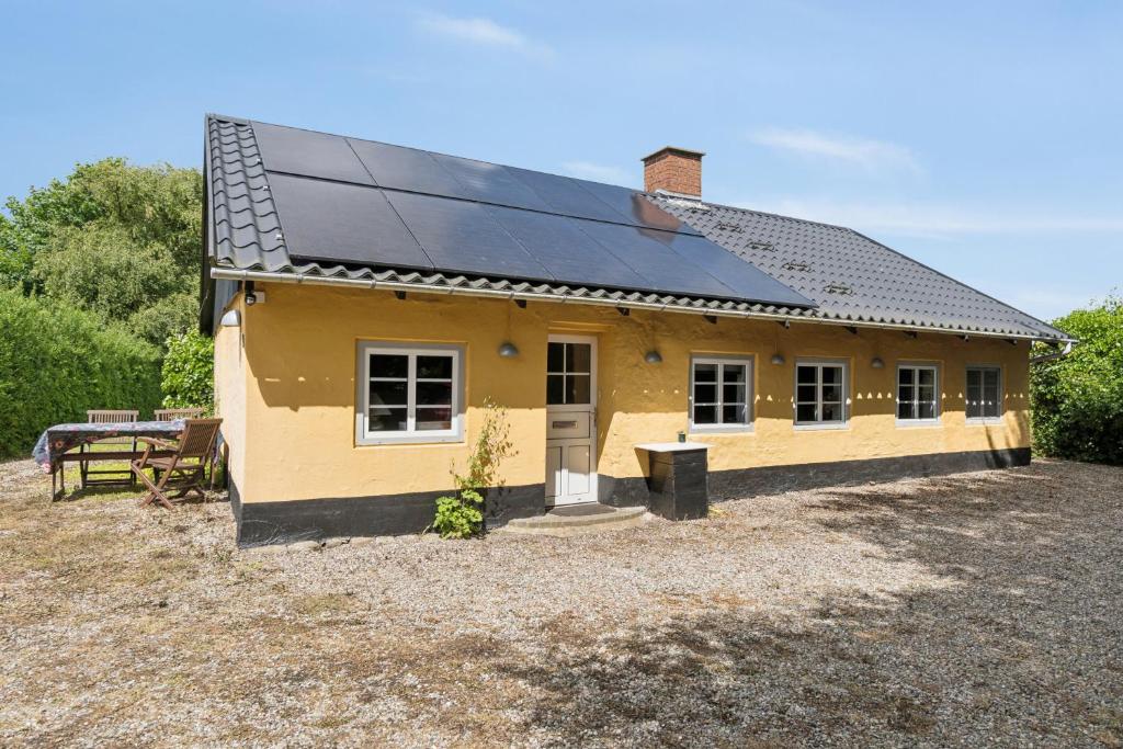 a small yellow house with a solar roof at Idyllic Old Cottage With Low Ceilings in Bredebro