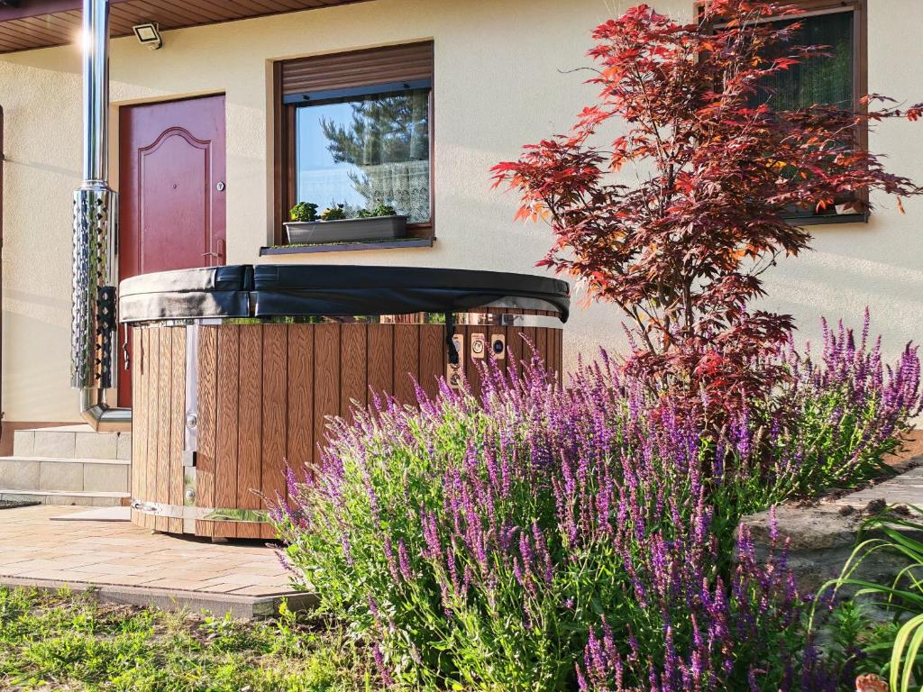 a house with a pink door and some purple flowers at Pszczeli Ogród - dom na wyłączność z jacuzzi ze świeżą wodą in Dęba Koliszowy