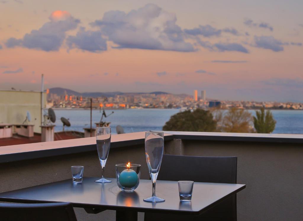 een tafel met twee wijnglazen en een kaars op een balkon bij Alilass Hotel in Istanbul