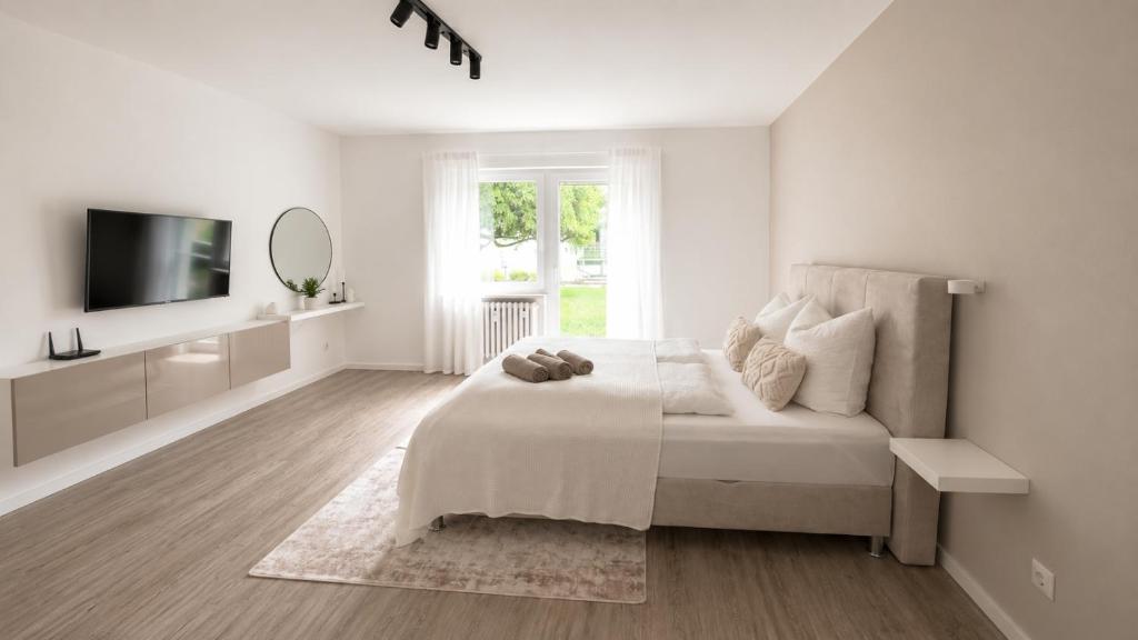 a white bedroom with a bed and a tv at Ferienwohnung an der Steinmauer in Bad Kissingen