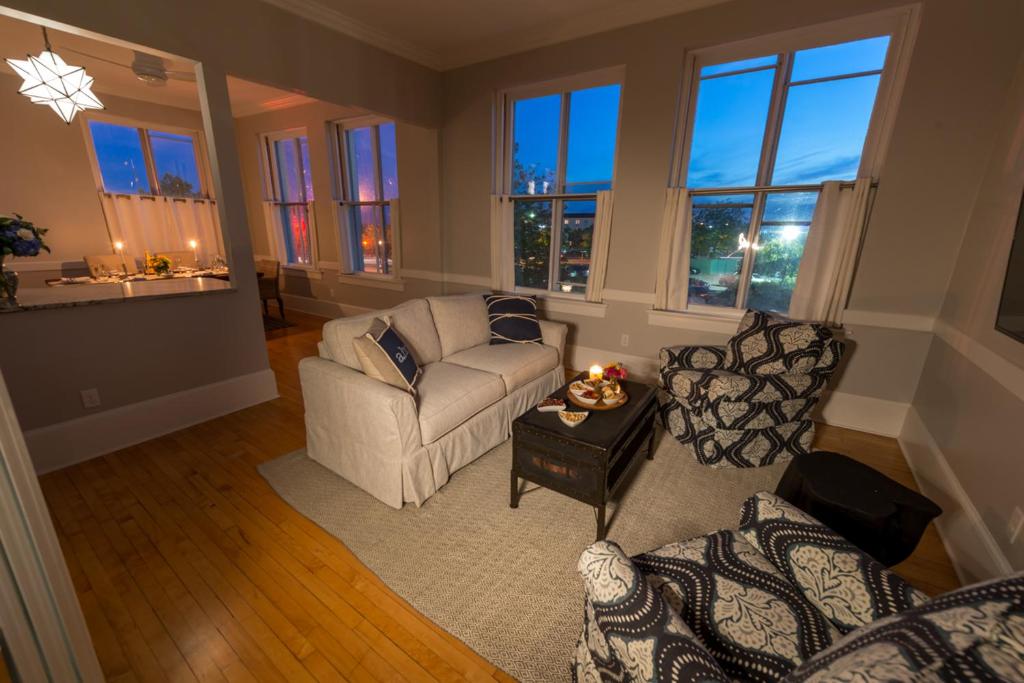 a living room with a couch and chairs and windows at The Newport Lofts - 194 Thames Street in Newport