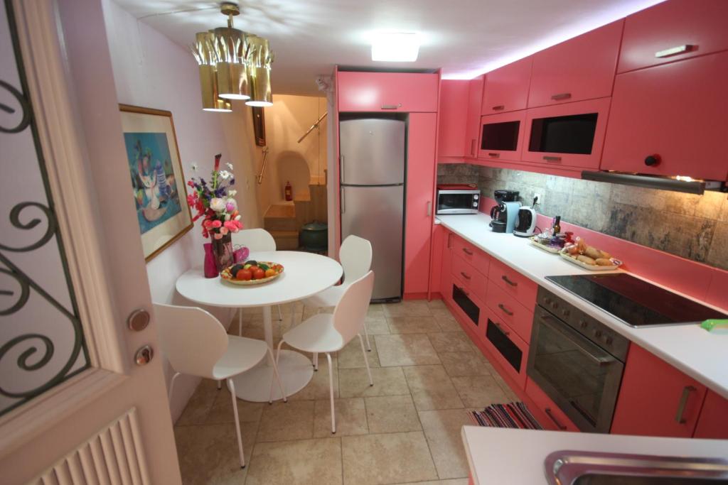 una cocina con armarios rojos y una mesa y sillas blancas. en A.K.Residence, en La Canea