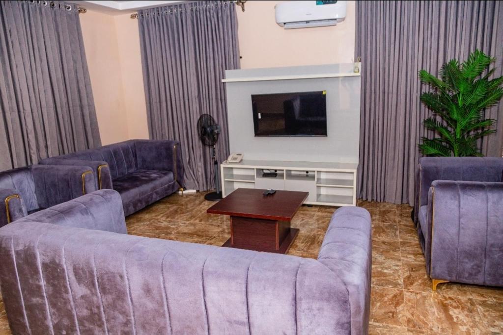 a living room with two couches and a tv at Seven Hills Suites in Makurdu