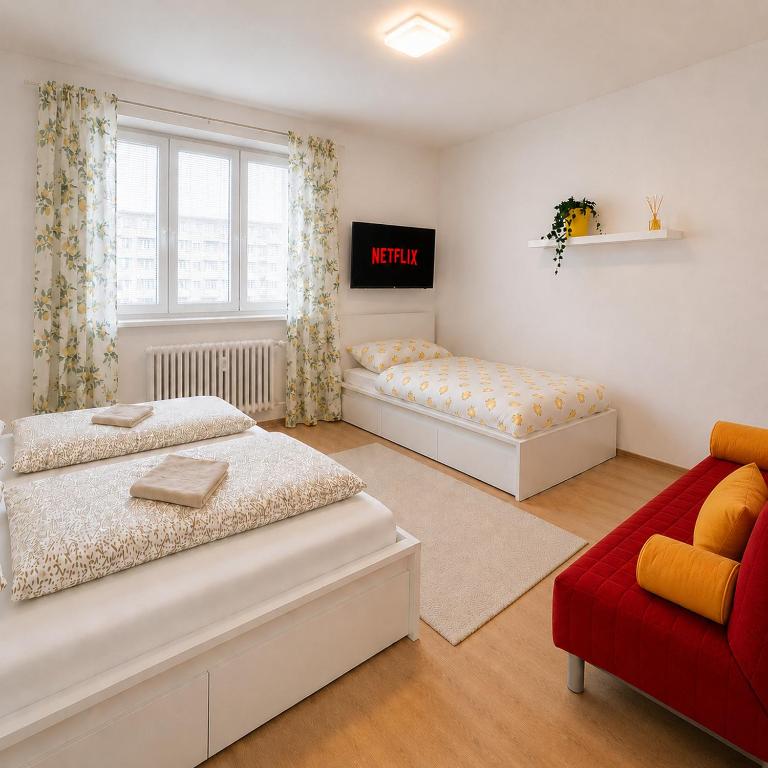 a bedroom with two beds and a red couch at Centrum apartment in Brno