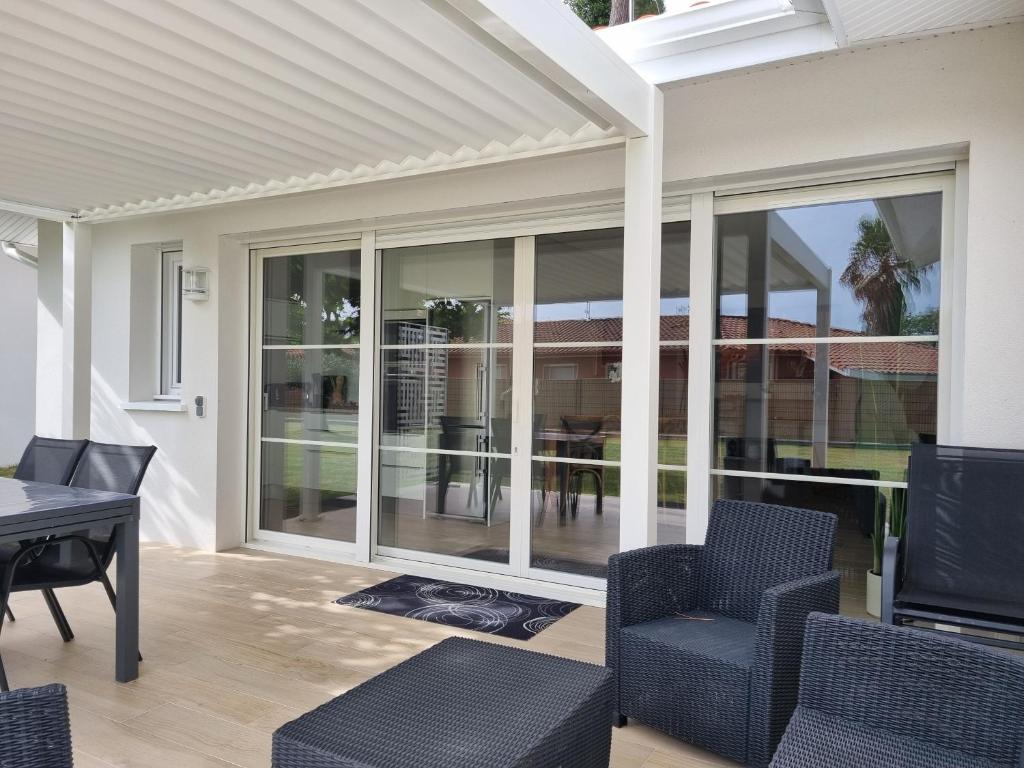 a patio with chairs and a table and glass doors at Bernard in Soustons
