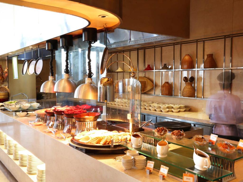 A brightly lit buffet counter displaying hot dishes, pastries and desserts.