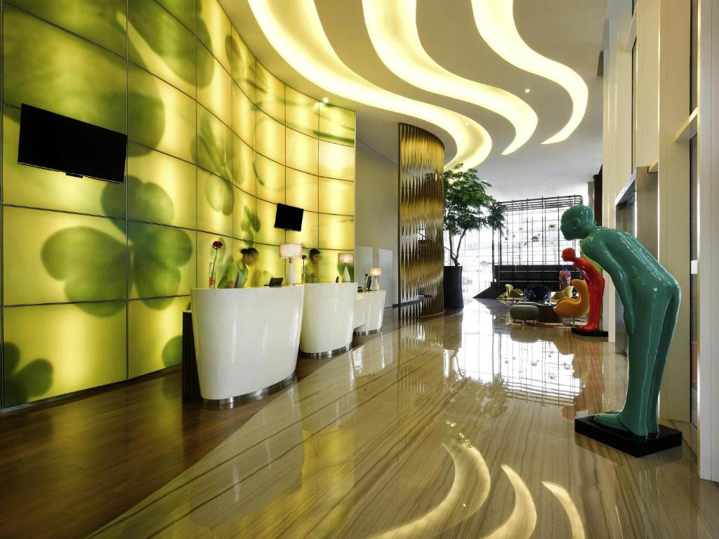 a lobby with a bar with white chairs and a large ceiling at All Seasons Jakarta Thamrin in Jakarta