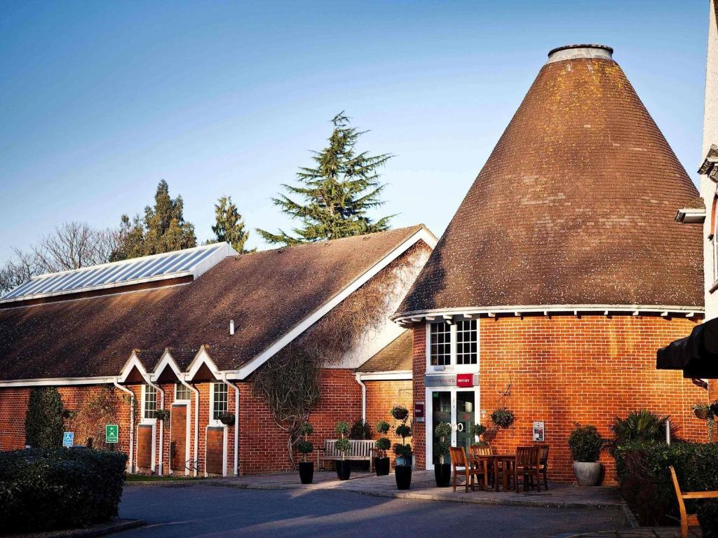 a large brick building with a large straw roof at Mercure Tunbridge Wells Hotel in Royal Tunbridge Wells