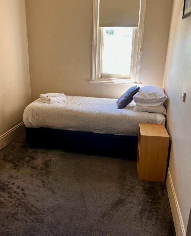 a small bedroom with a bed with a window at Branxholm Hotel in Branxholm