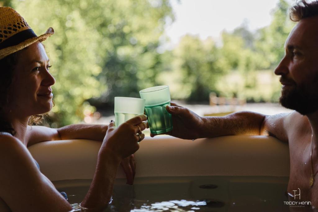 two people in a bathtub holding glasses of water at La Bulle au bord de l'eau in Épagne-Épagnette