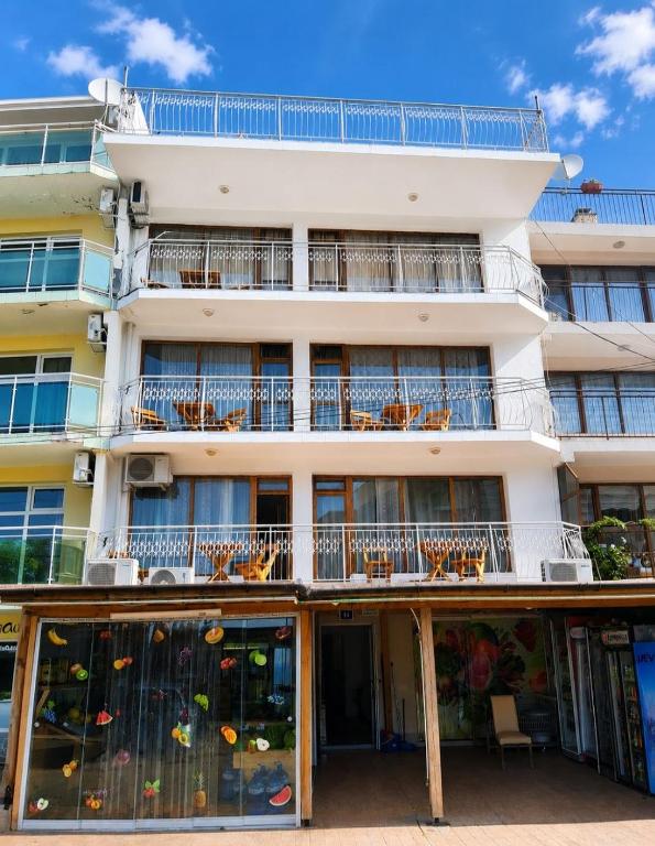 a large white building with windows and chairs at Къща за гости Уют in Sveti Vlas