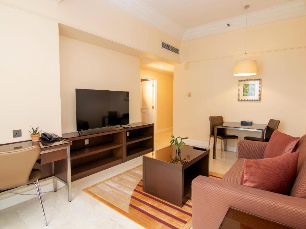 A combined living and dining area with a sofa, desk and television.