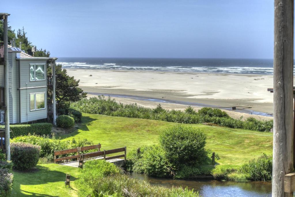 uma vista para uma praia com uma casa e um banco em Little Creek Cove Beach Resort em Newport