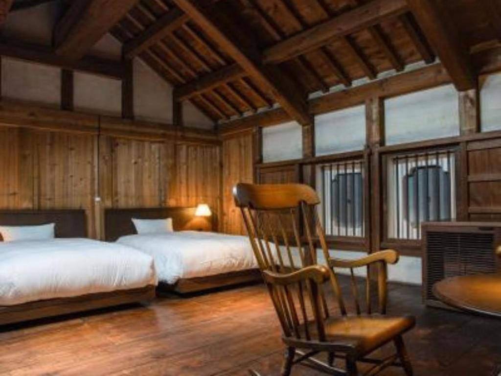 a bedroom with two beds and a rocking chair at NIPPONIA HOTEL Ozu Castle Town in Ōzu