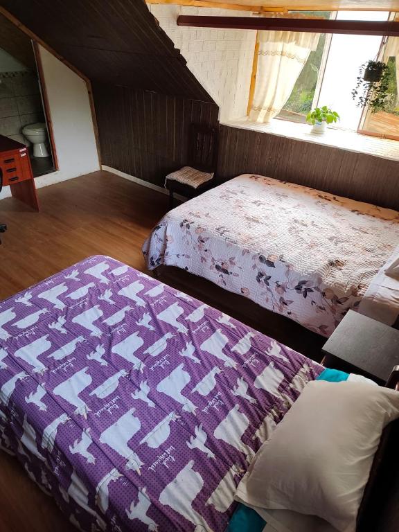 a bedroom with two beds and a purple blanket at Yanesh Haus habitaciones Oxapampa in San Antonio