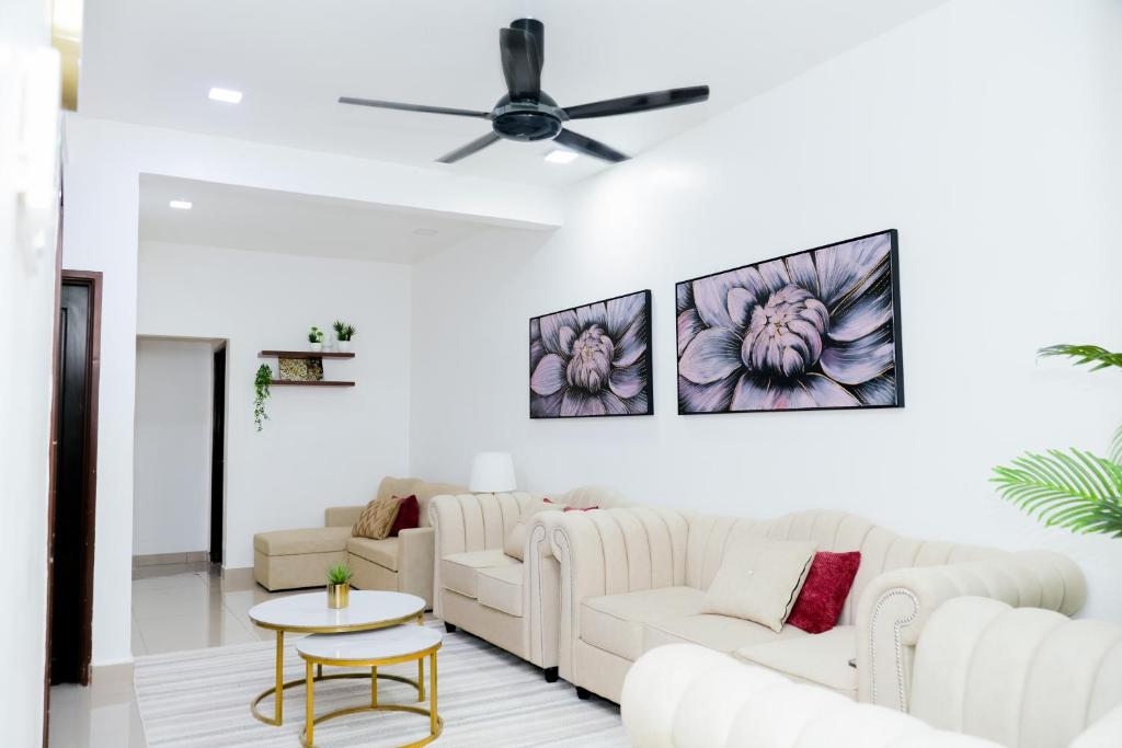 a living room with white furniture and a ceiling fan at Aisya homestay jerteh in Jertih