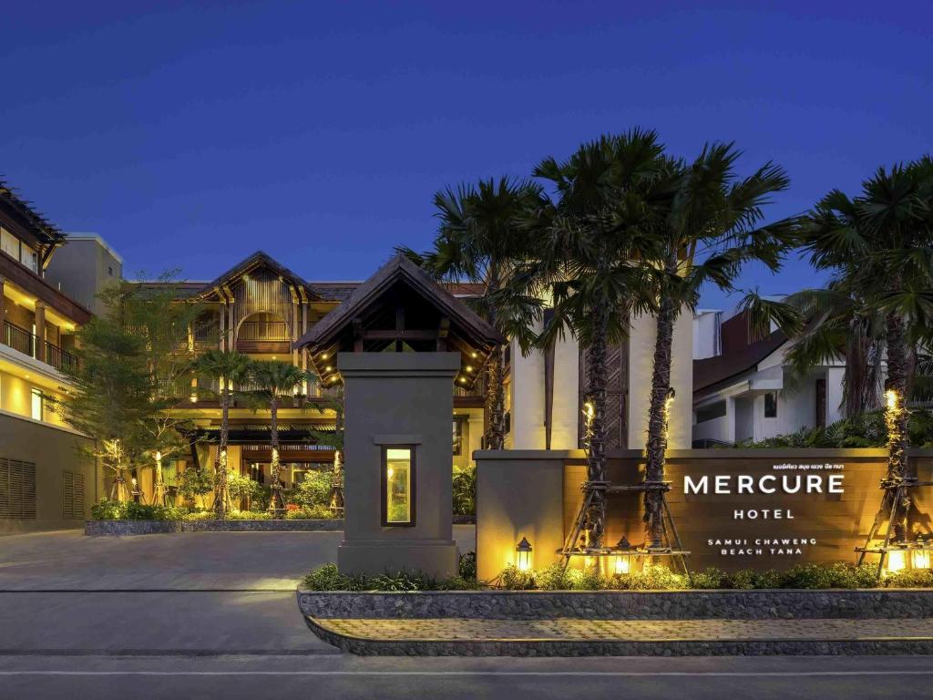 a hotel with a welcome sign and palm trees at night at Mercure Samui Chaweng Tana in Chaweng
