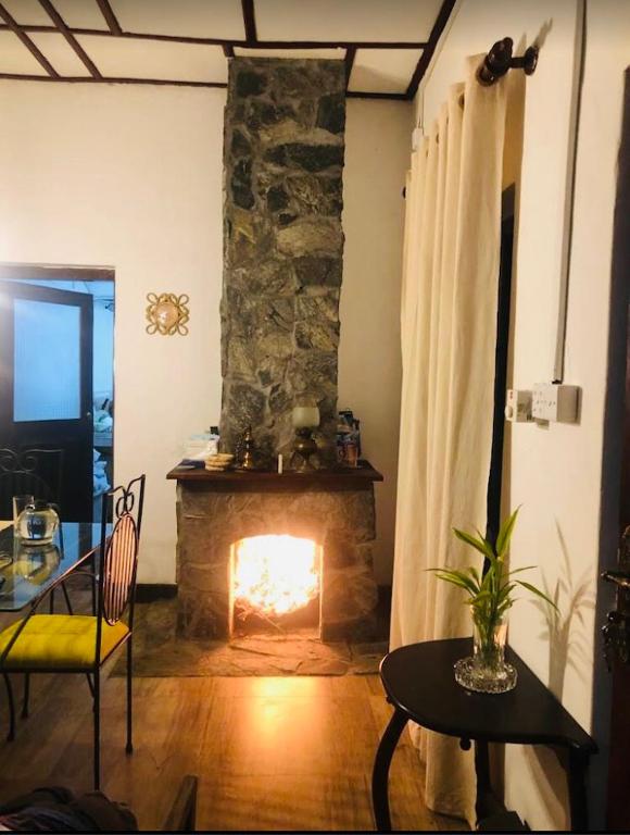 a living room with a fireplace and a table and chairs at Koshi's Country Cottage Ella in Ella