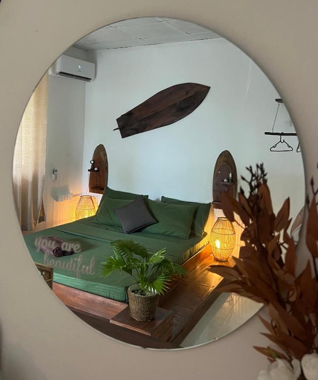 a bedroom with a green bed and a mirror at AmoreBay in Mirissa