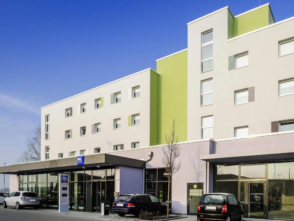 a building with cars parked in front of it at Ibis budget München Airport Erding in Erding