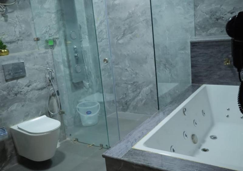 a bathroom with a shower and a toilet and a tub at Hotel Capital in Noida