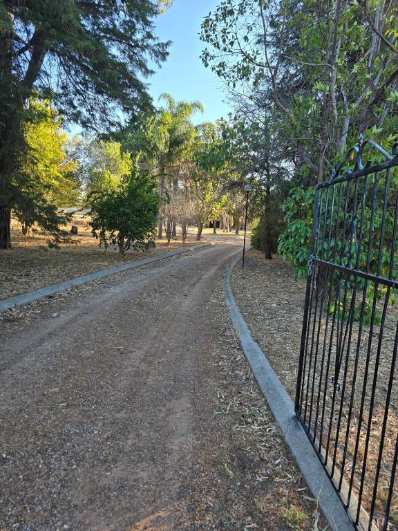 an open gate on a dirt road with trees at Sansa Farmhouse in Kelmscott