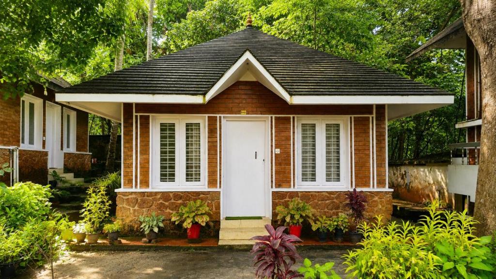 a small house with a white door in a yard at K Cottage in Varkala