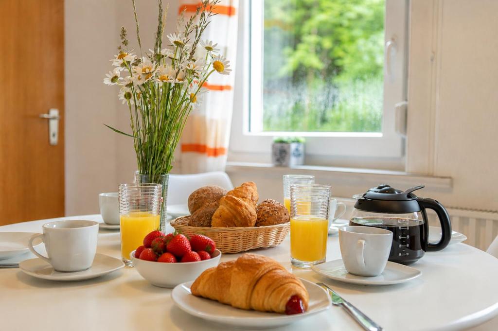a breakfast table with croissants and fruit and orange juice at Harzurlaub mit 2 Hunden - FeWo Alte Schule in Sankt Andreasberg in Sankt Andreasberg