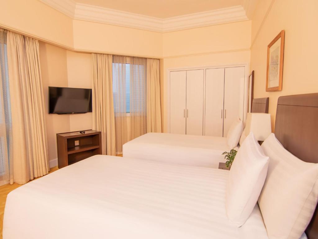 A twin bedroom with two beds, a television and a full-width wardrobe.