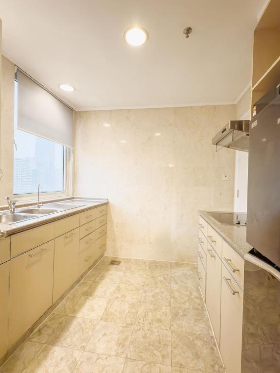 A long galley kitchen with a sink, cabinets and a city-facing window.
