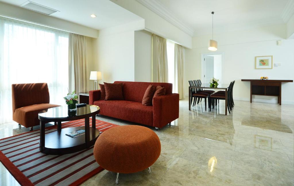 A spacious sitting and dining area with a red sofa and polished stone floor.