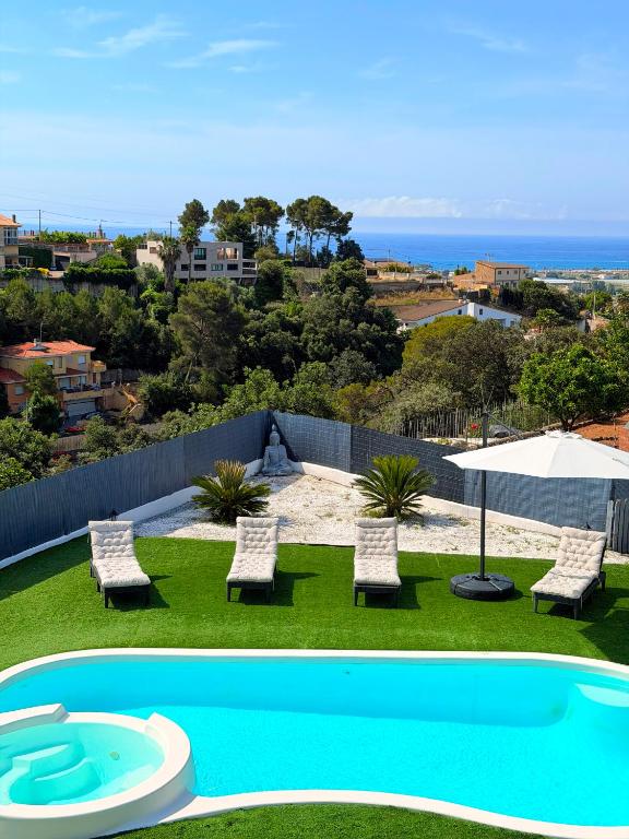 a view of a pool with chairs and an umbrella at Chillout House with heated pool 29 C Sea & Mountain view in Santa Susanna