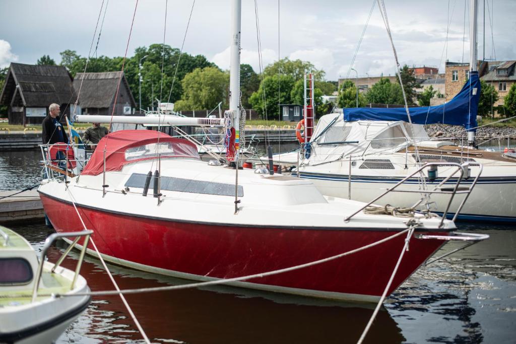 a red boat docked in a marina with other boats at Jahta Engures ostā in Engure