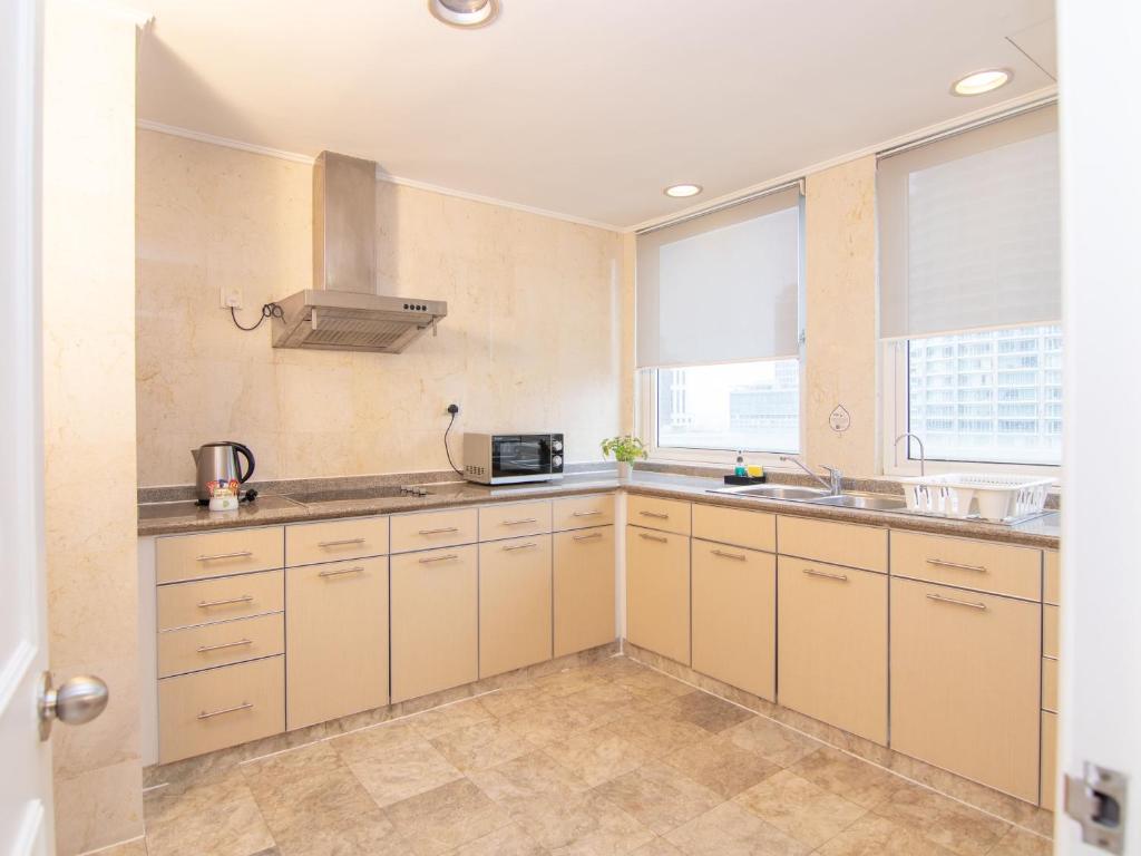 A bright apartment kitchen with wraparound cabinets, two sinks and city views.