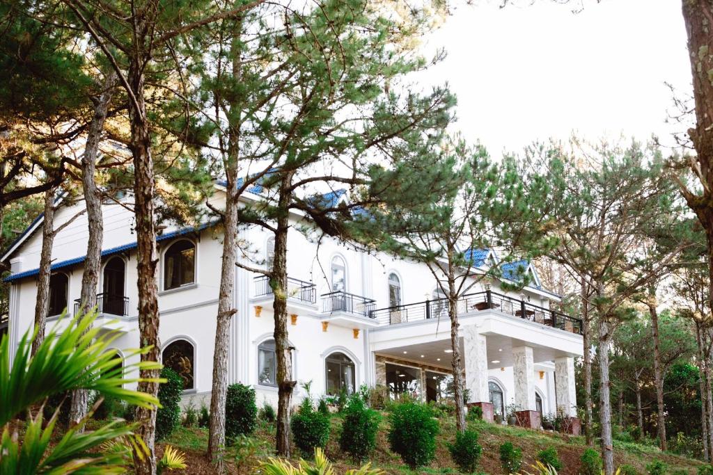 a white house with trees in front of it at Gia An Hotel Dalat in Da Lat