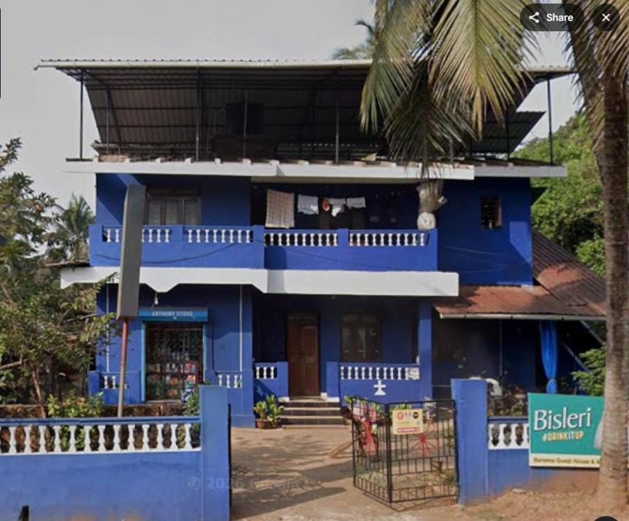 a blue house with a palm tree in front of it at Benema Guest House in Benaulim