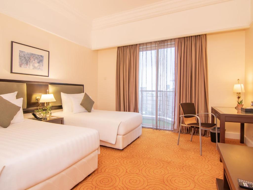 A twin room with a balcony door, small desk and separate seating area.