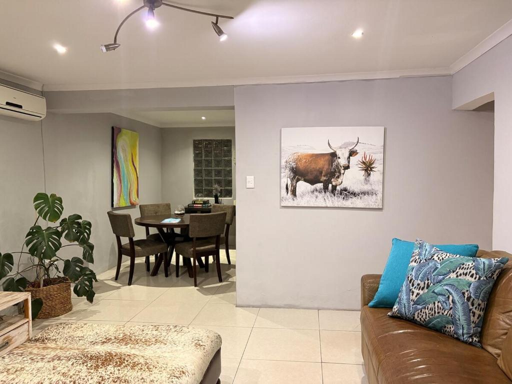 a living room with a cow painting on the wall at Local Roots in Pinetown