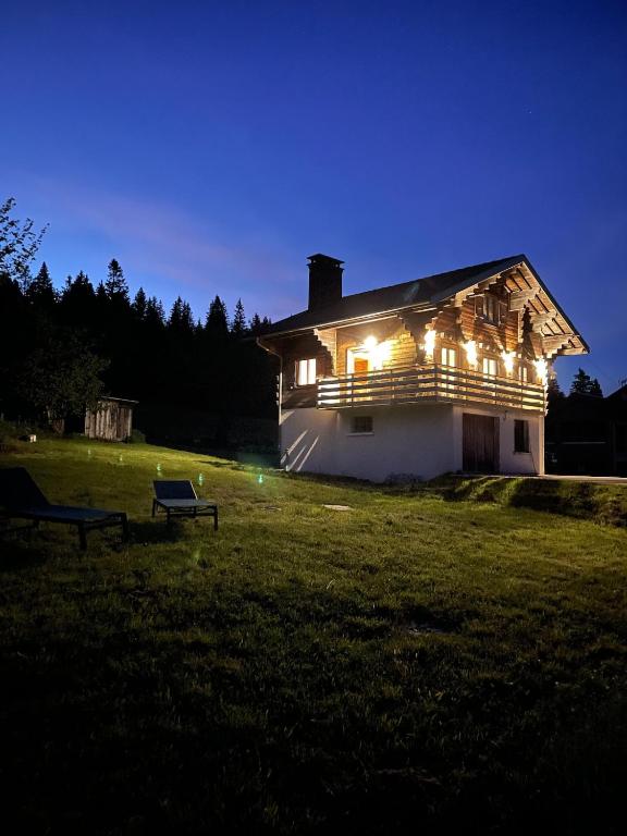 a house lit up at night in a field at Chalet Les Balcons du Risoux in Bellefontaine