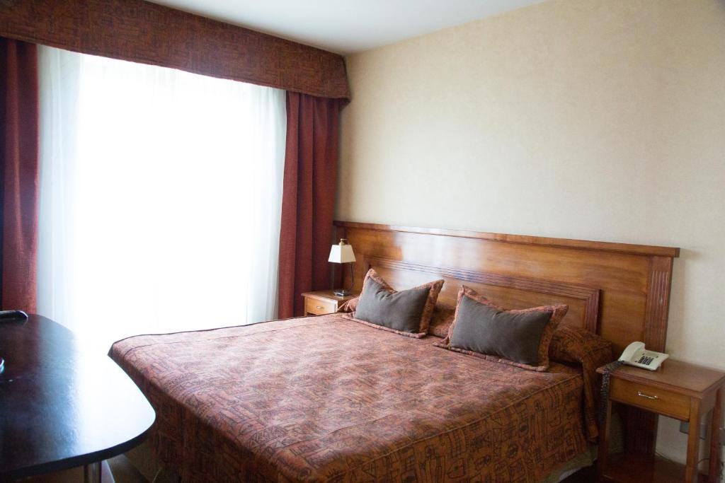 a bedroom with a bed with a telephone and a window at Millenium Mendoza Apartments in Mendoza