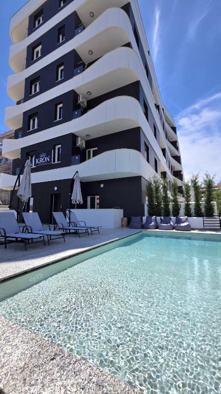 a hotel with a swimming pool in front of a building at Kron Apart Hotel Golem in Golem