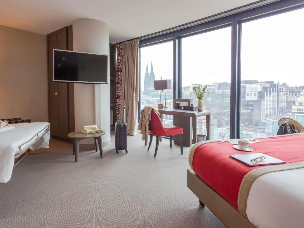 a hotel room with two beds and a desk at Mercure Clermont Ferrand centre Jaude in Clermont-Ferrand