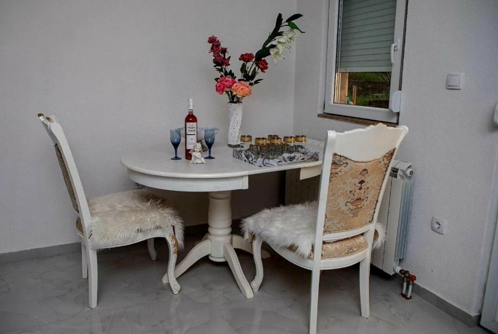 a white table with two chairs and a bottle of wine at Apartmani Katarina in Donje Čičevo