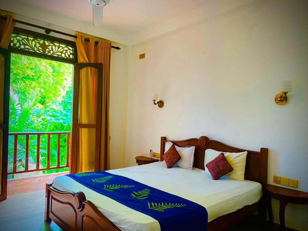 a bedroom with a bed and a large window at Raniya Villa in Bentota